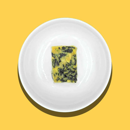 Small rectangular miso block with seaweed on a white plate against yellow background